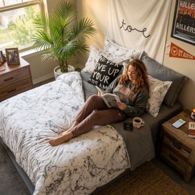 adolescente regardant revue sur parures de lit blanche