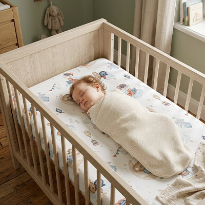 bebe emmaillote dans bassinette sur drap housse bebe