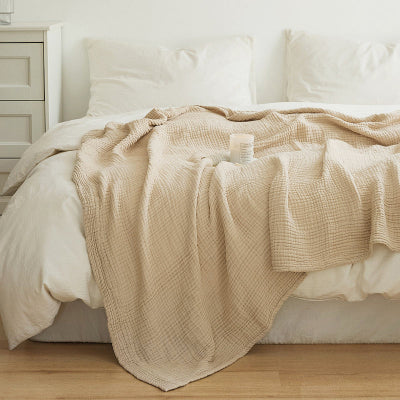 couverture beige déposée sur lit