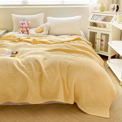 couverture jaune sur lit avec coussin et peluche