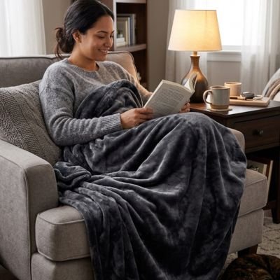 femme lisant dans fauteuil enveloppé dans plaid