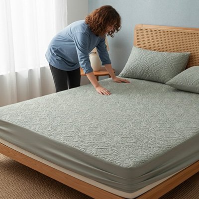 femme placant protege matelas gris sur lit