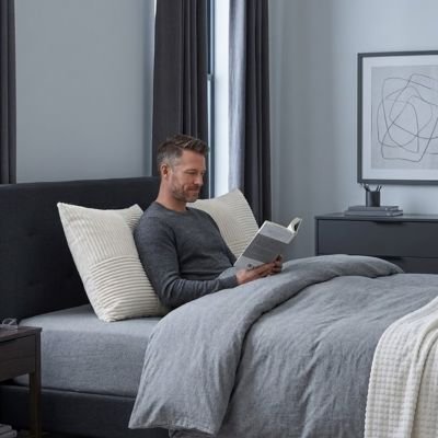 homme dans lit lisant avec housse de coussin patchwork