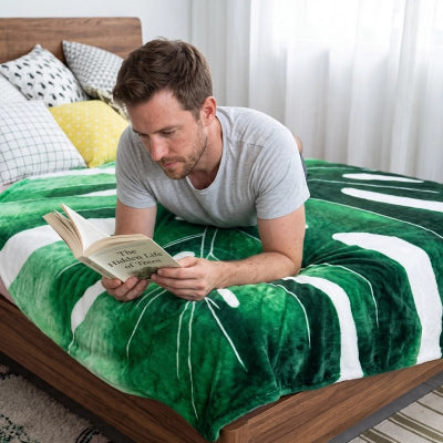 homme étendu sur couvre lit feuille tropicale avec livre