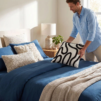 homme plaçant housses de coussin noires sur lit