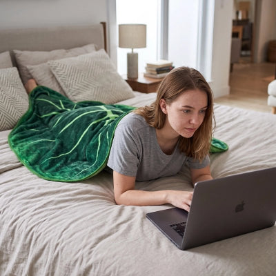 jeune femme travaillant sur portable sous couvre lit feuille tropicale