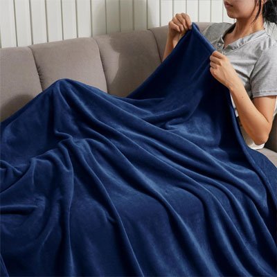 jeune fille assise sur canapé se couvrant avec couverture