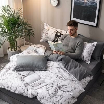 jeune homme lisant avec parures de lit blanche