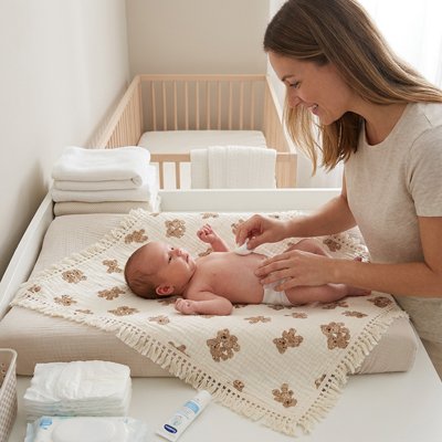 maman faisant toilette bébé sur couverture emmaillotage bébé