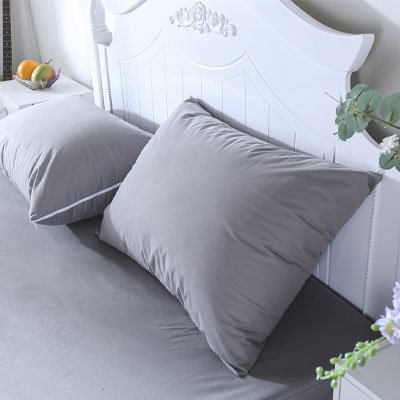 taie doreiller grise adossé a tête de lit